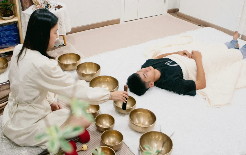 sound healer playing singing bowls in a calm room