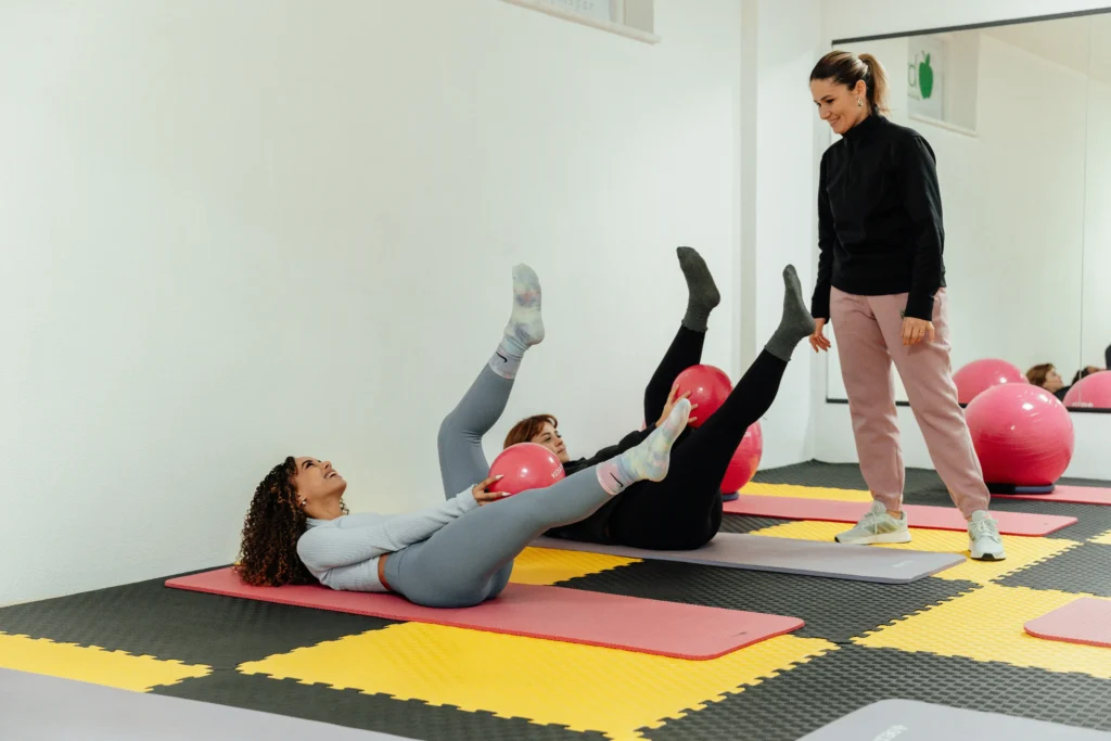 Personal trainer assisting a postpartum woman with core exercises.